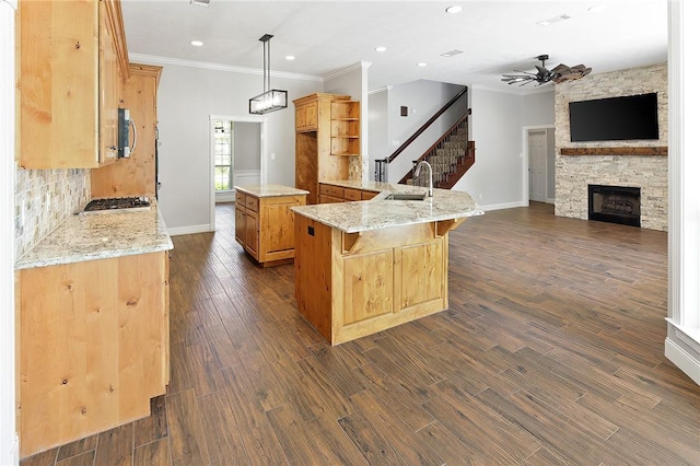 kitchen with light stone counters, a breakfast bar, sink, a kitchen island, and hanging light fixtures