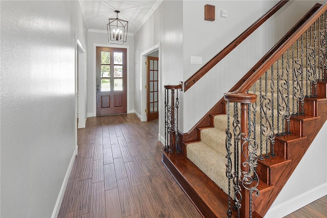 foyer featuring crown molding, dark wood-type flooring, and an inviting chandelier