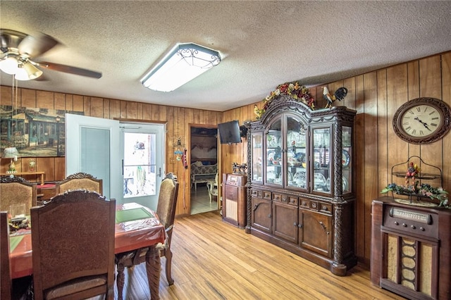 885 7th St, Somerville, TX 77879 - dining room with wood walls, a textured ceiling, ceiling fan, and light wood-type flooring