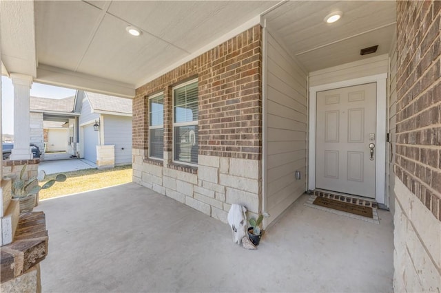 view of exterior entry with covered porch and brick siding