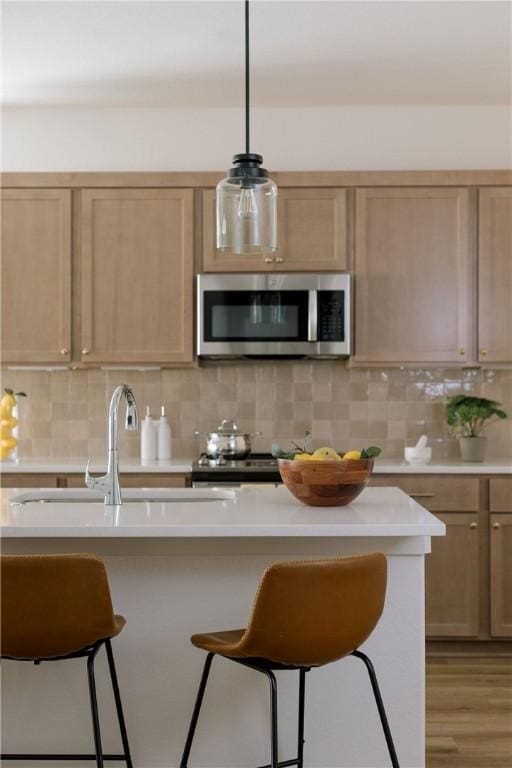 kitchen featuring pendant lighting, a breakfast bar, backsplash, and appliances with stainless steel finishes