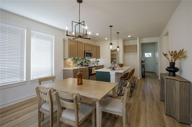 dining space with a notable chandelier, sink, and light hardwood / wood-style flooring