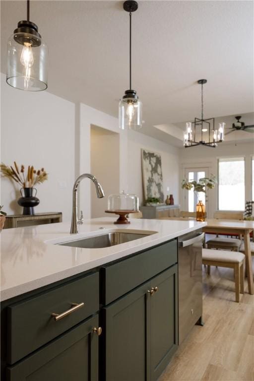 kitchen featuring decorative light fixtures, light hardwood / wood-style floors, stainless steel dishwasher, and sink