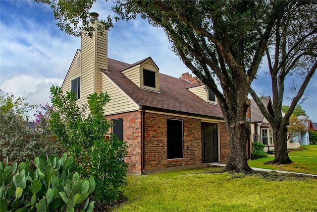 view of front of home with brick siding, a chimney, and a front lawn
