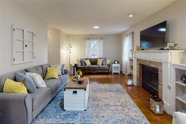 living room with dark wood-type flooring, recessed lighting, and a fireplace