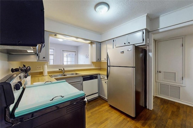 kitchen featuring visible vents, freestanding refrigerator, white dishwasher, light countertops, and a sink