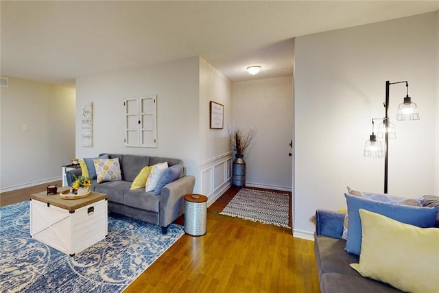 living room featuring baseboards, visible vents, and wood finished floors