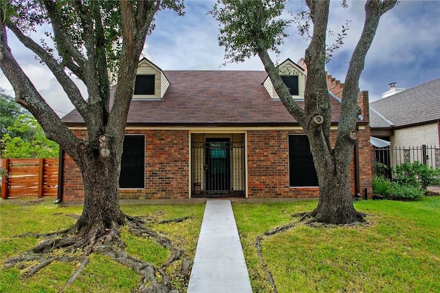 view of front of house with brick siding, fence, and a front lawn