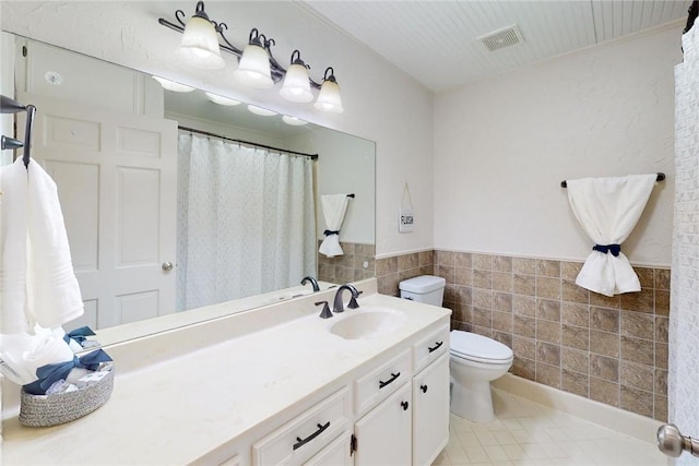 bathroom featuring visible vents, tile walls, tile patterned floors, a wainscoted wall, and toilet