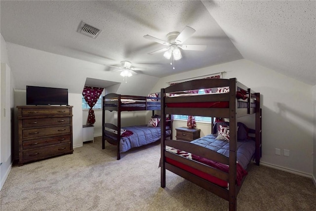 carpeted bedroom with a textured ceiling, a ceiling fan, baseboards, lofted ceiling, and visible vents
