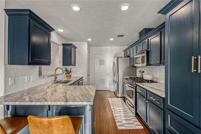 kitchen with sink, decorative backsplash, dark hardwood / wood-style flooring, a kitchen bar, and stainless steel appliances