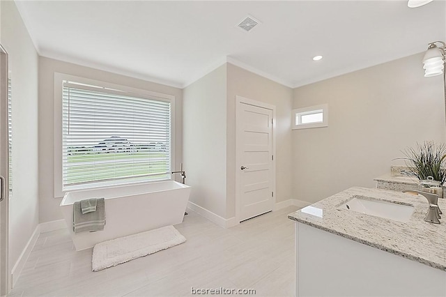 bathroom featuring a tub to relax in, vanity, and a healthy amount of sunlight