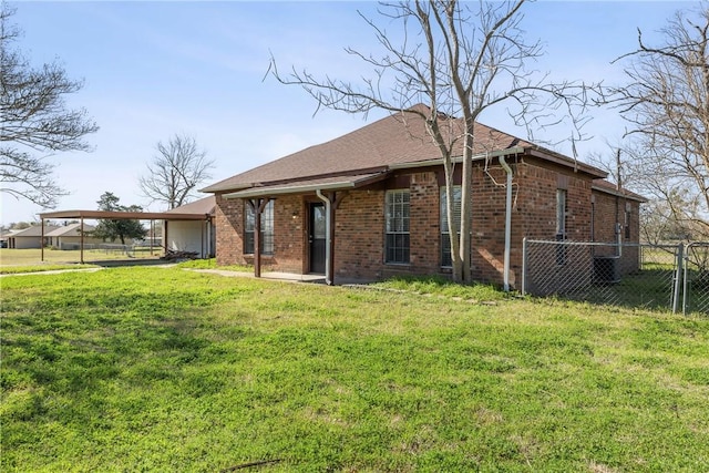 back of property with a gate, fence, a yard, a carport, and brick siding