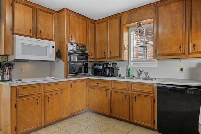 kitchen featuring a sink, black appliances, brown cabinetry, and light countertops