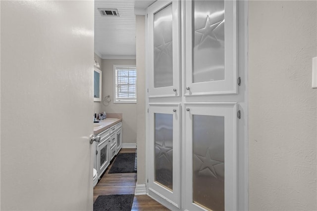 bathroom with visible vents, vanity, a textured wall, and wood finished floors