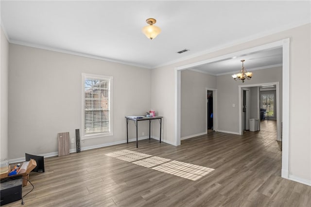 spare room featuring an inviting chandelier, wood finished floors, baseboards, and visible vents