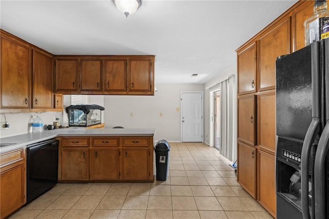 kitchen with black appliances, brown cabinetry, light tile patterned floors, and light countertops