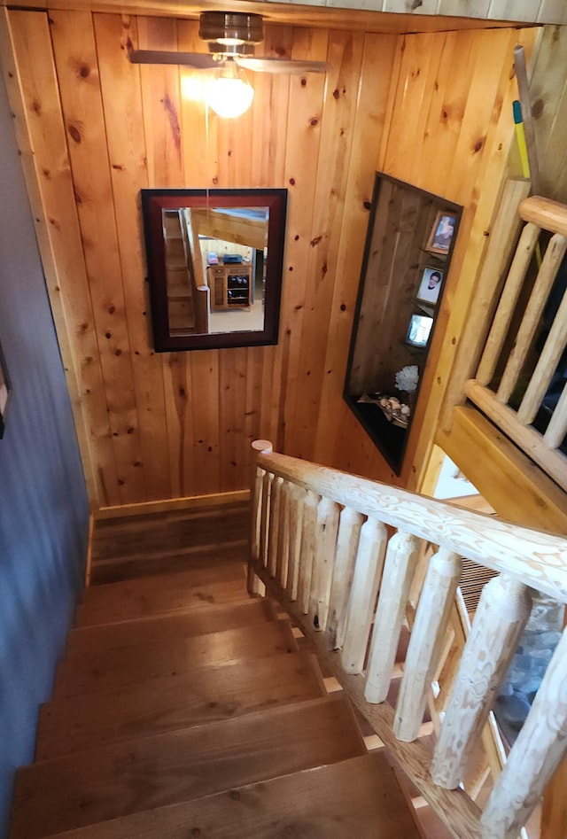 staircase with wood finished floors and wooden walls