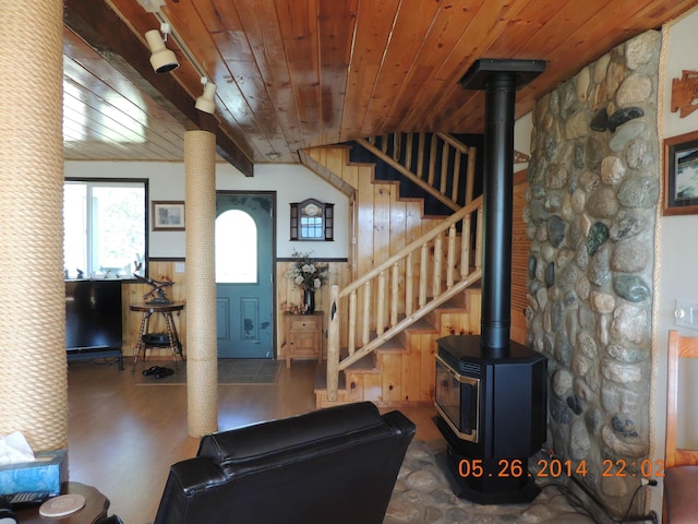 living room featuring wood ceiling, stairway, and a wood stove