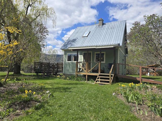 back of house with a yard, a deck, metal roof, and a chimney