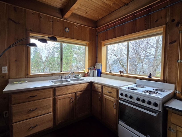 kitchen with wood ceiling, a sink, light countertops, wooden walls, and white range with electric stovetop