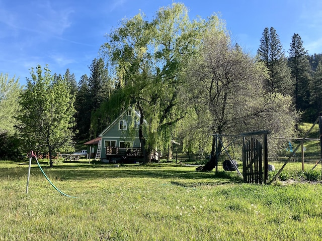 view of yard with a deck, fence, and a forest view