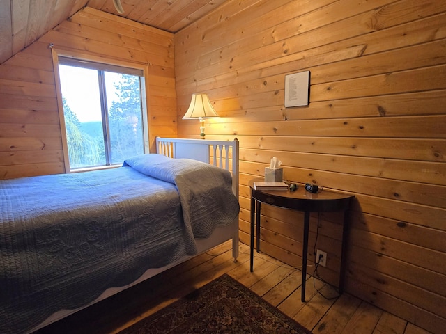 bedroom with lofted ceiling, wooden walls, hardwood / wood-style floors, and wooden ceiling