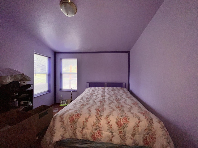 bedroom featuring a textured ceiling and vaulted ceiling