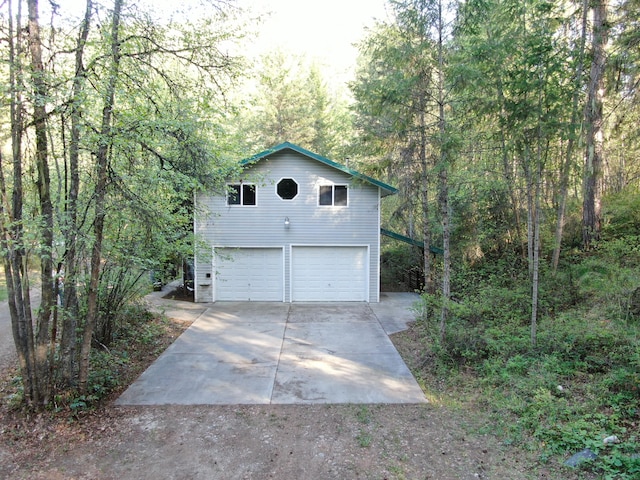 garage with concrete driveway and a wooded view