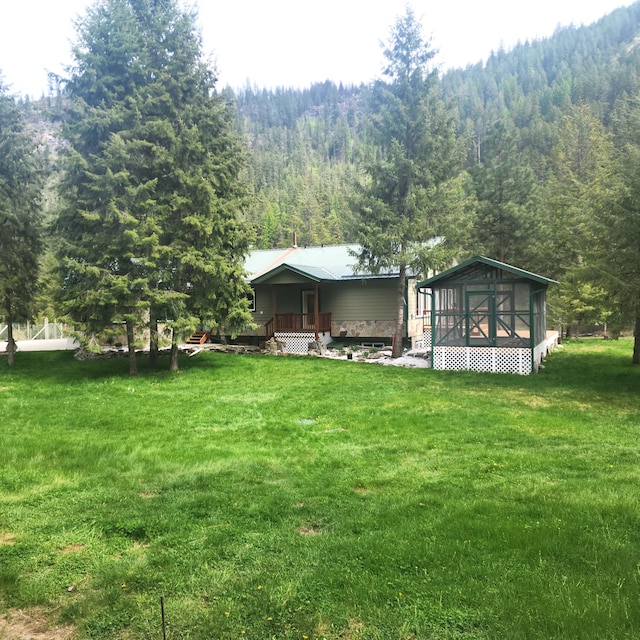 view of yard with a deck and a view of trees