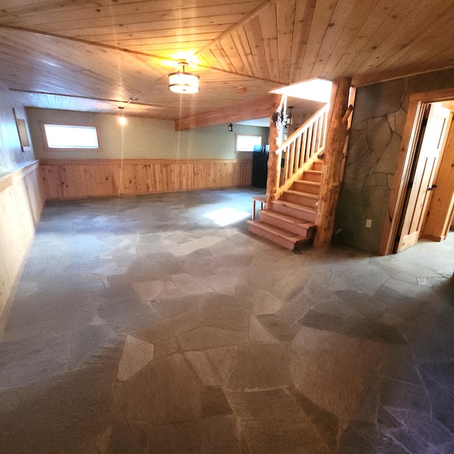 basement with wainscoting, wood ceiling, plenty of natural light, and stairway