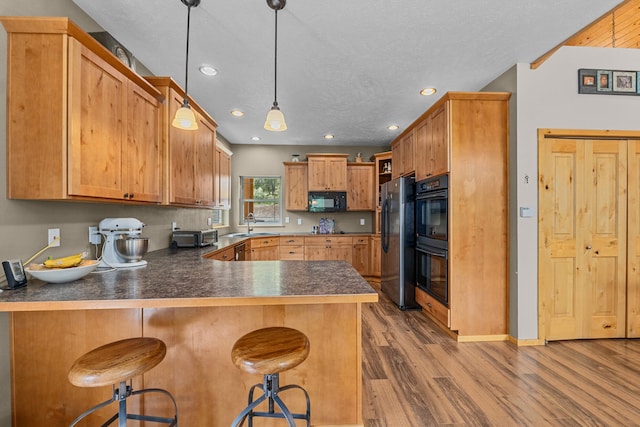 1157 Orin-Rice Rd, Colville, WA 99114 - kitchen with black appliances, a peninsula, dark countertops, wood finished floors, and recessed lighting