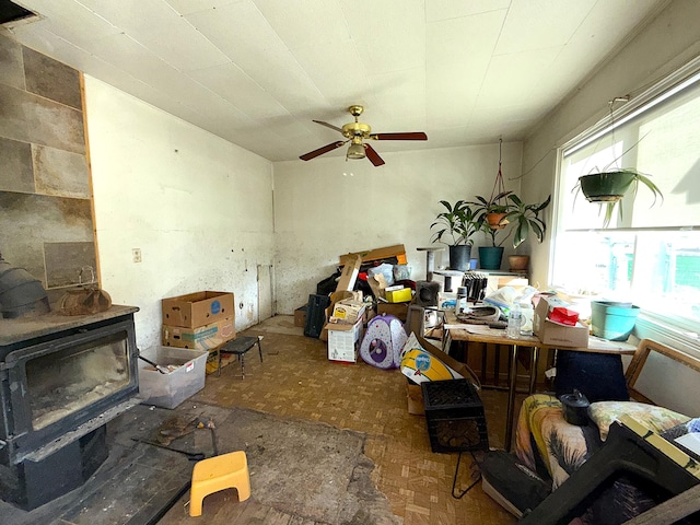 misc room with a wood stove, ceiling fan, plenty of natural light, and parquet flooring