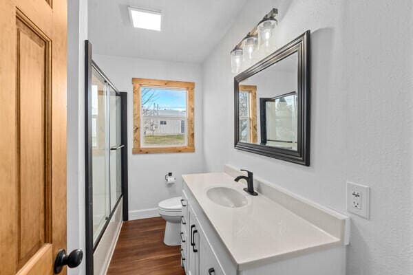 bathroom with vanity, hardwood / wood-style floors, an enclosed shower, and toilet