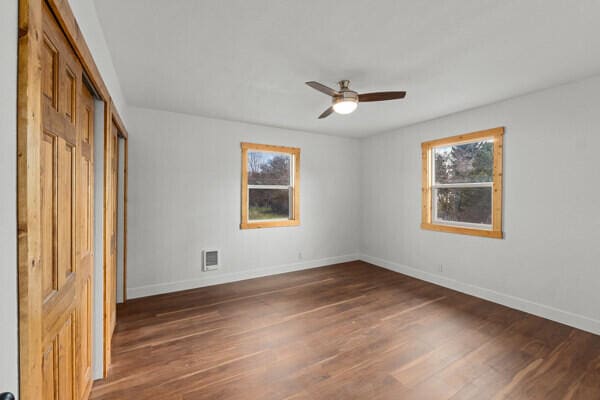 unfurnished bedroom with dark wood-type flooring, ceiling fan, and a closet