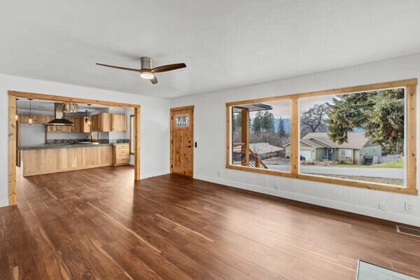 unfurnished living room with dark hardwood / wood-style floors and ceiling fan