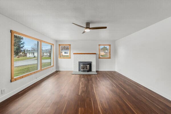 unfurnished living room with dark hardwood / wood-style floors and ceiling fan