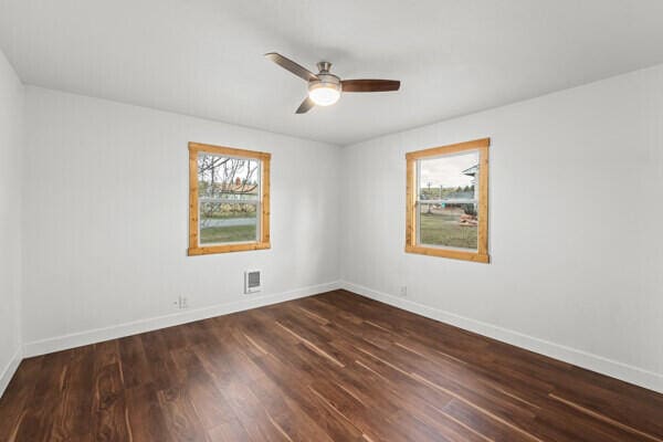 spare room with dark wood-type flooring and ceiling fan