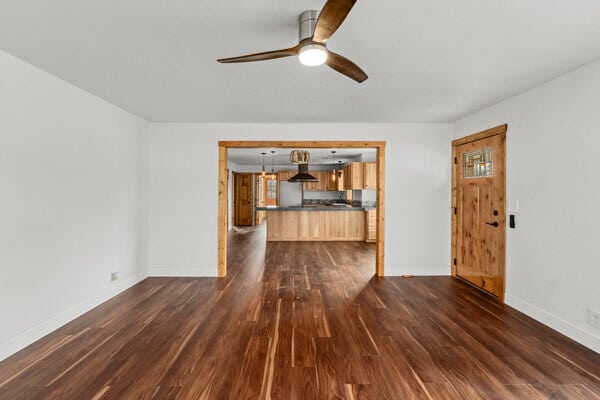 unfurnished living room featuring dark hardwood / wood-style flooring and ceiling fan