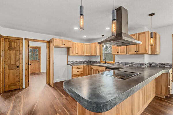 kitchen with dark hardwood / wood-style floors, pendant lighting, sink, island exhaust hood, and black electric stovetop