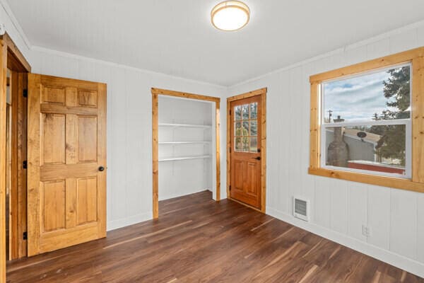 unfurnished bedroom featuring crown molding, dark wood-type flooring, and a closet