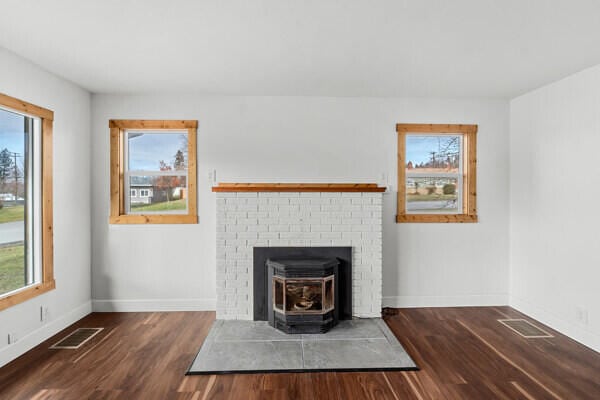 unfurnished living room with dark hardwood / wood-style floors and a wood stove