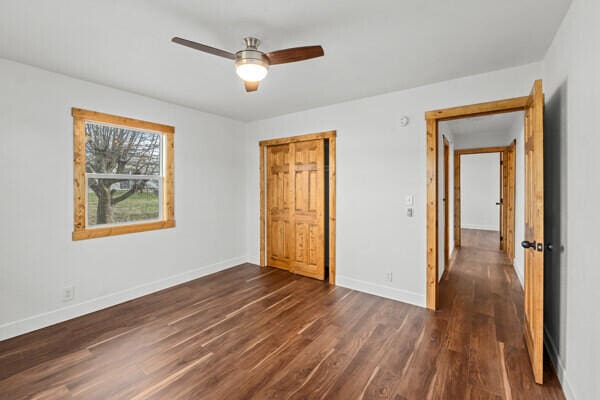 unfurnished bedroom with dark wood-type flooring, ceiling fan, and a closet