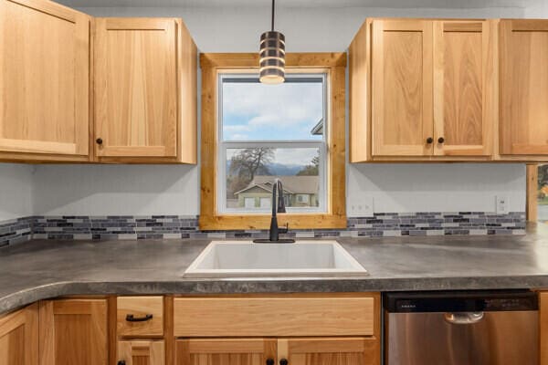 kitchen featuring sink, decorative light fixtures, stainless steel dishwasher, and backsplash