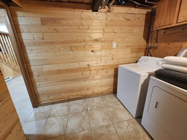 washroom featuring cabinets, light tile patterned floors, wood walls, and independent washer and dryer