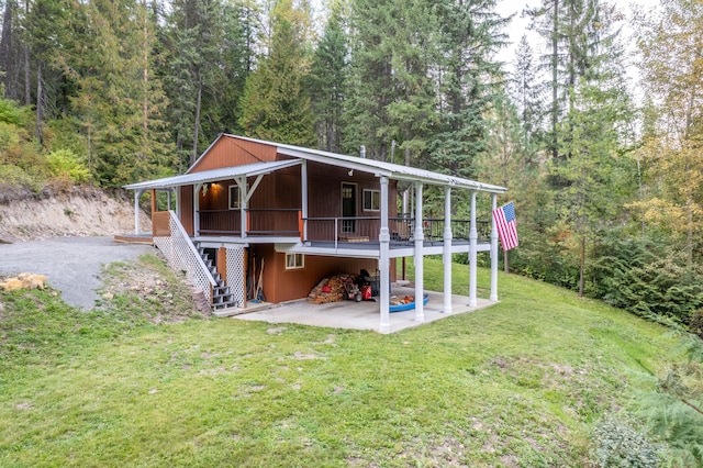 back of house with a wooden deck, a yard, and a patio