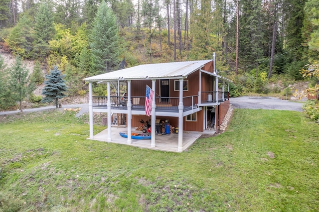 rear view of property with a patio area, a wooden deck, and a lawn