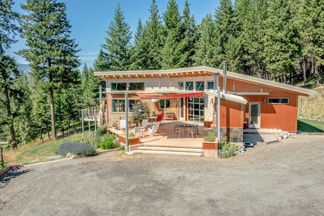 view of front facade with a wooden deck and a view of trees