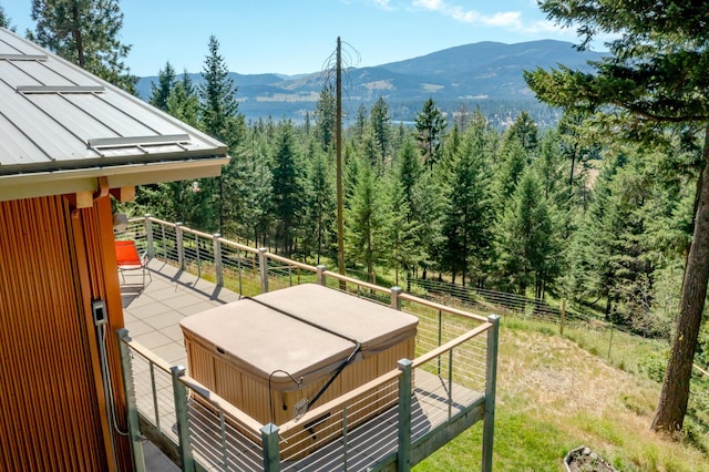 exterior space featuring a hot tub, a wooded view, and a mountain view