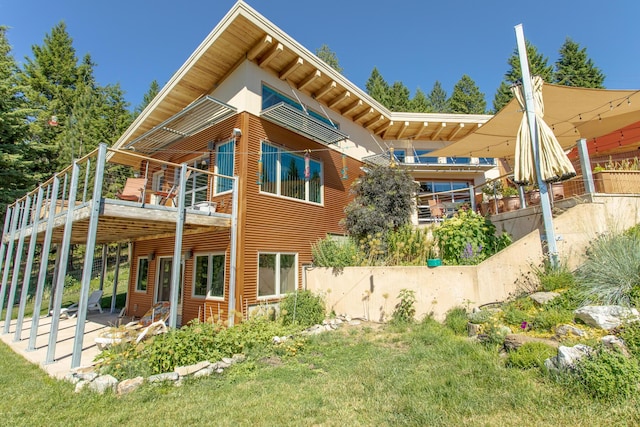 rear view of property with fence, a wooden deck, a yard, and a patio